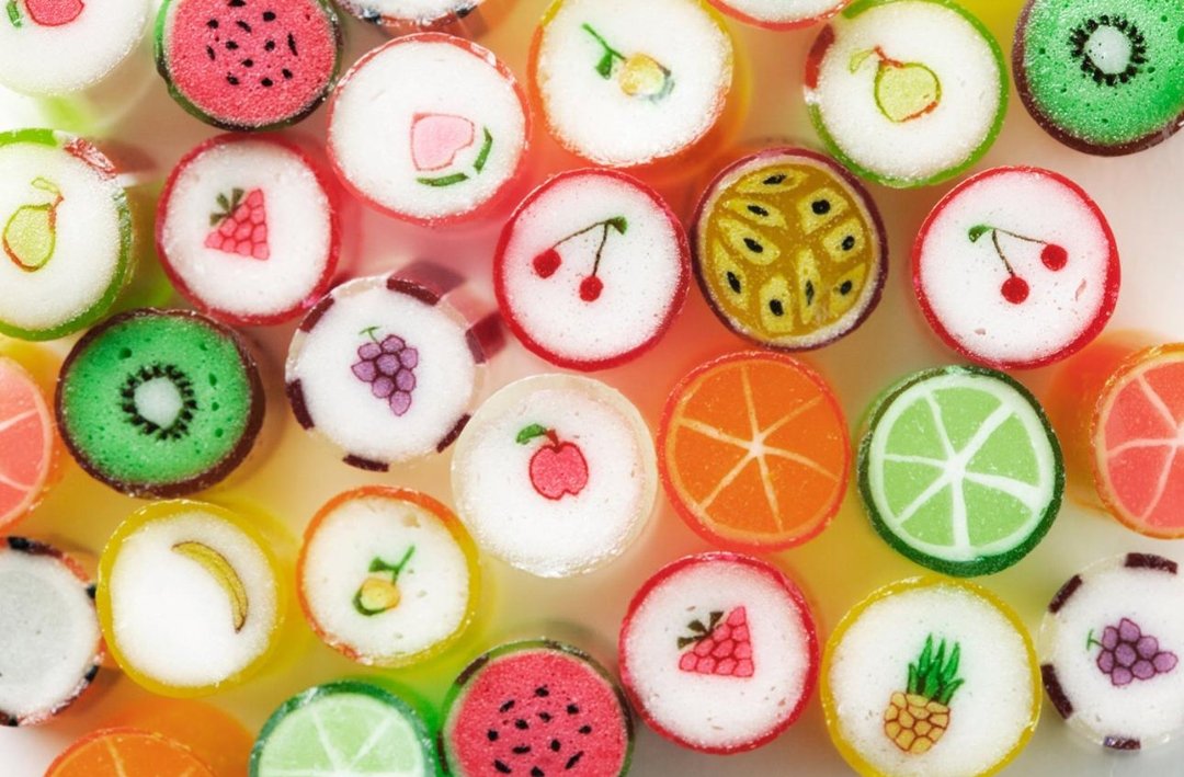 Top-down view of many rock-candy pieces, each with a different fruit pattern
